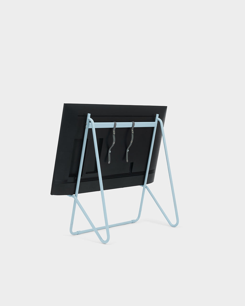 Rear view of Bloom Stands Low in Powder Blue holding a black TV, showing A-frame tube legs and leather straps
