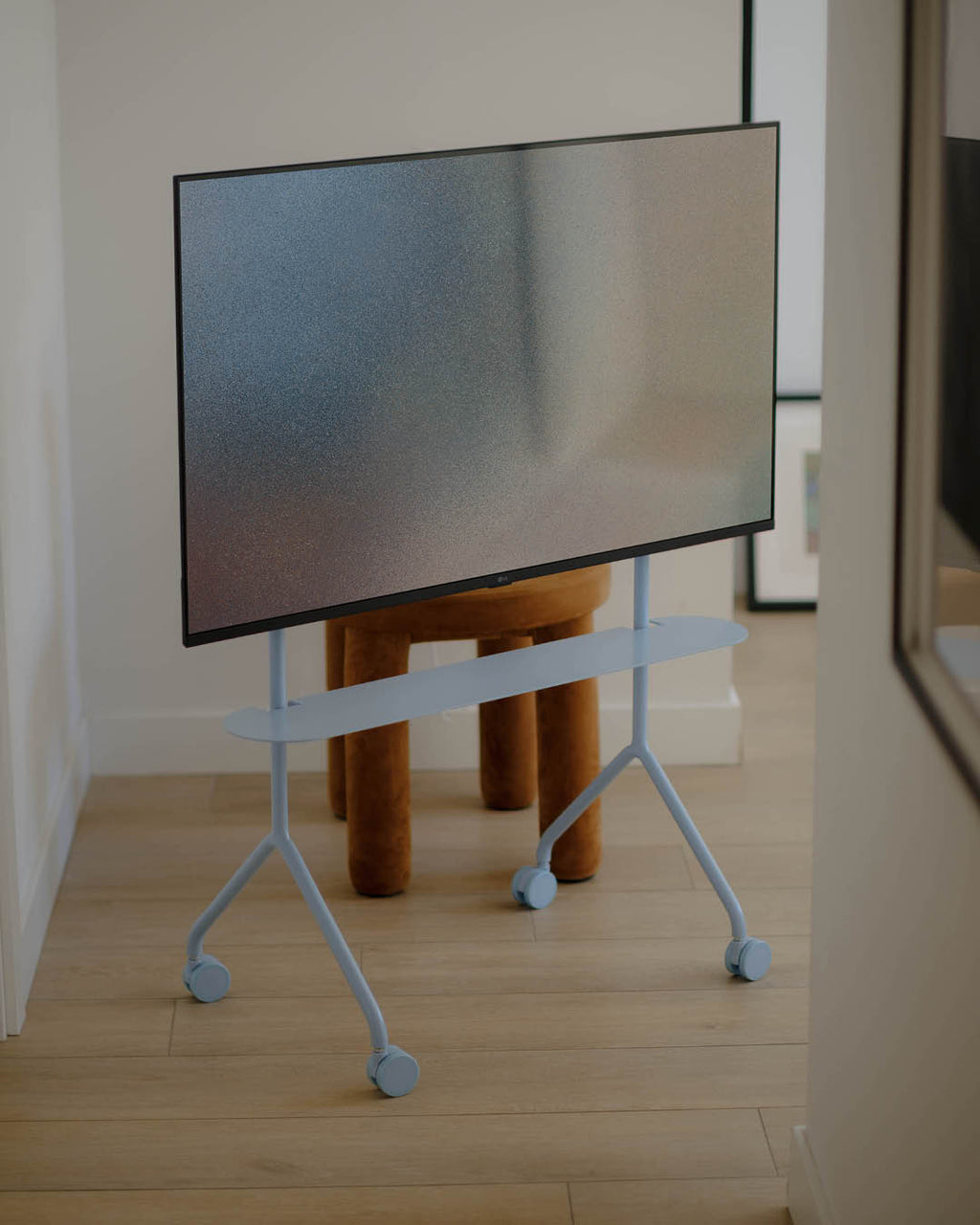 Moon Light TV stand in Powder Blue, angled studio view showing empty VESA mount bracket, tall legs and caster wheels