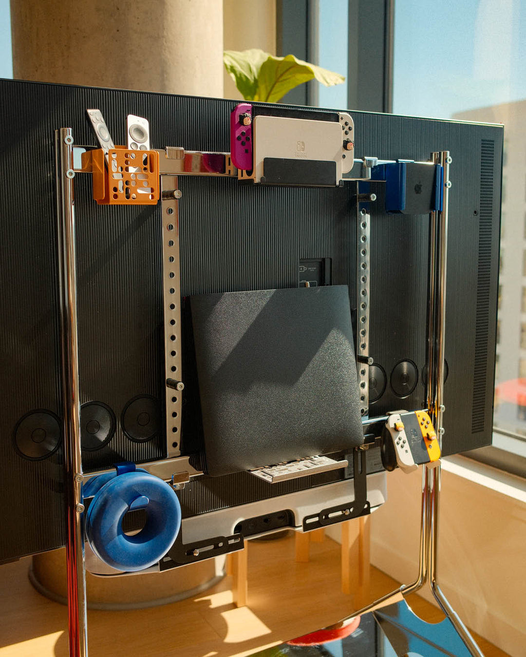 Nintendo Switch 2 Mount in Pearl holding a docked console behind a wall-mounted TV, with remotes and Joy-Cons nearby