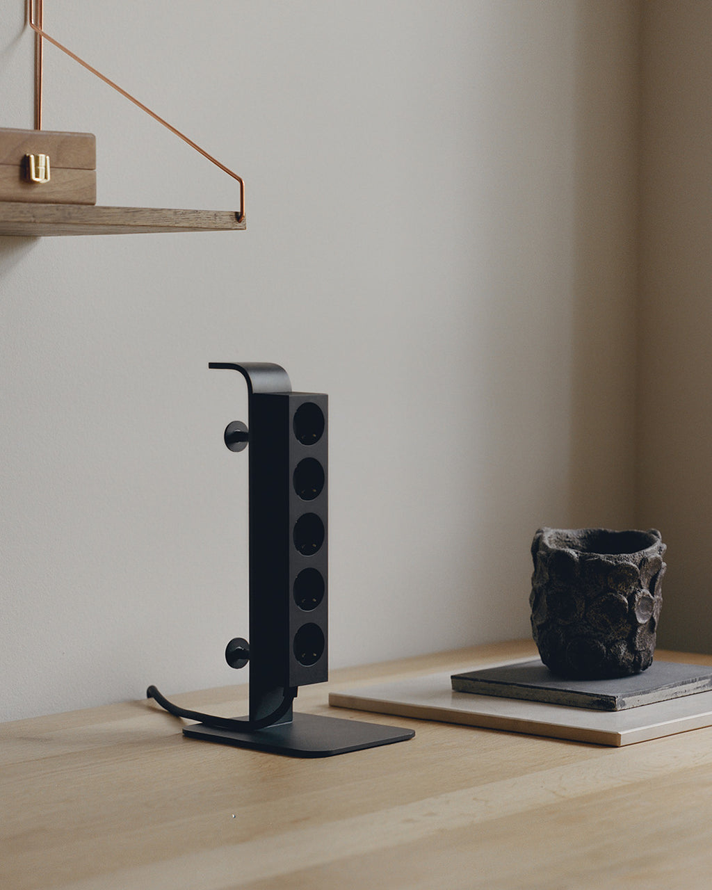 Charcoal Power Tower standing on its square base, angled studio view showing five sockets and coiled cord with plug
